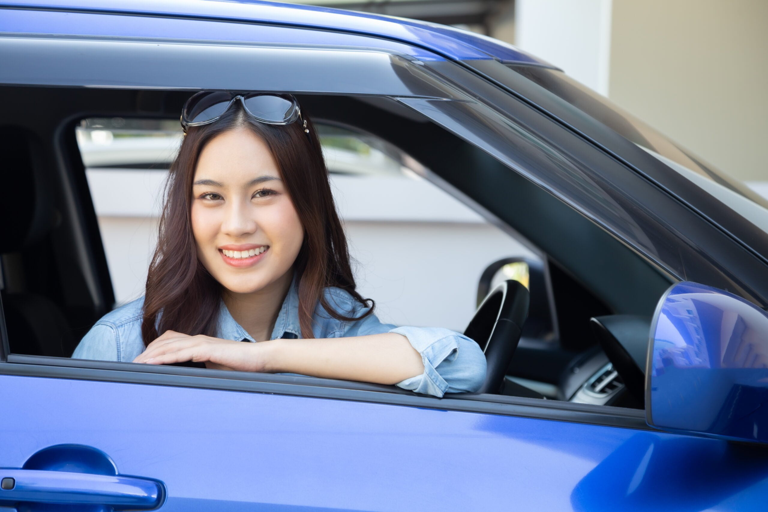 asian woman driving car smile happily with glad positive expression during drive travel journey people enjoy laughing transport drive thru concept scaled
