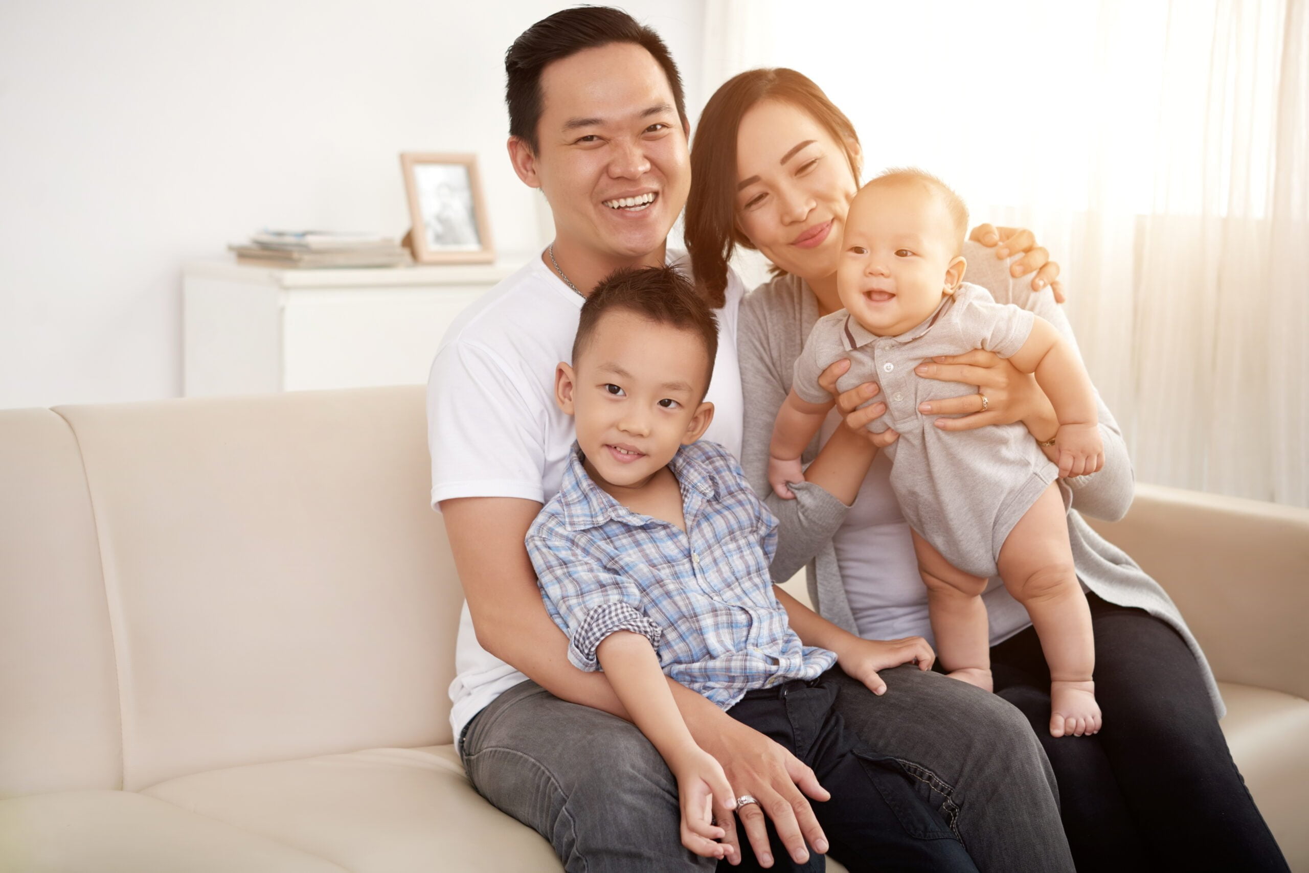 loving asian couple posing couch home with young son baby scaled