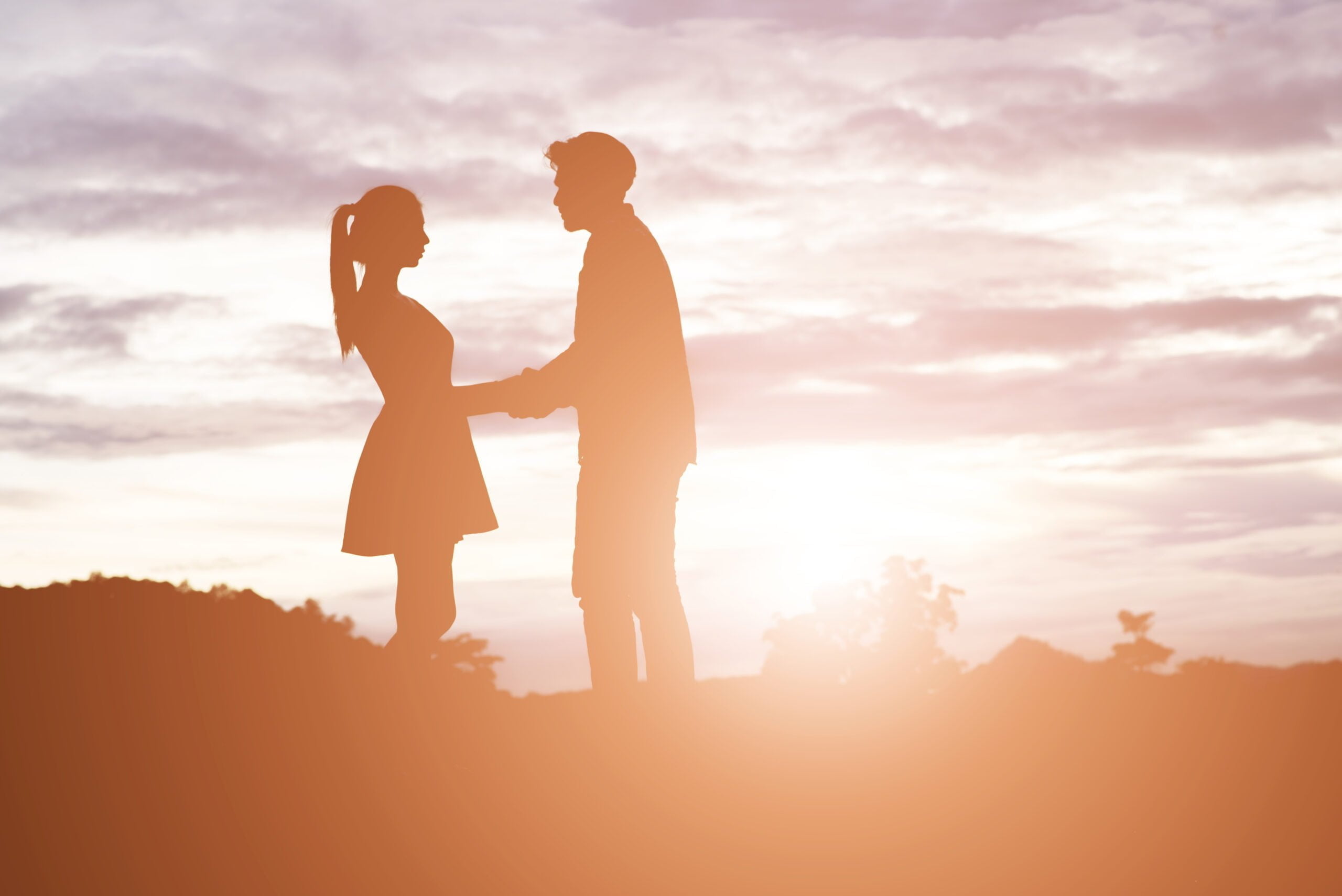 silhouette young couple holding hands with mountain sunset ba scaled
