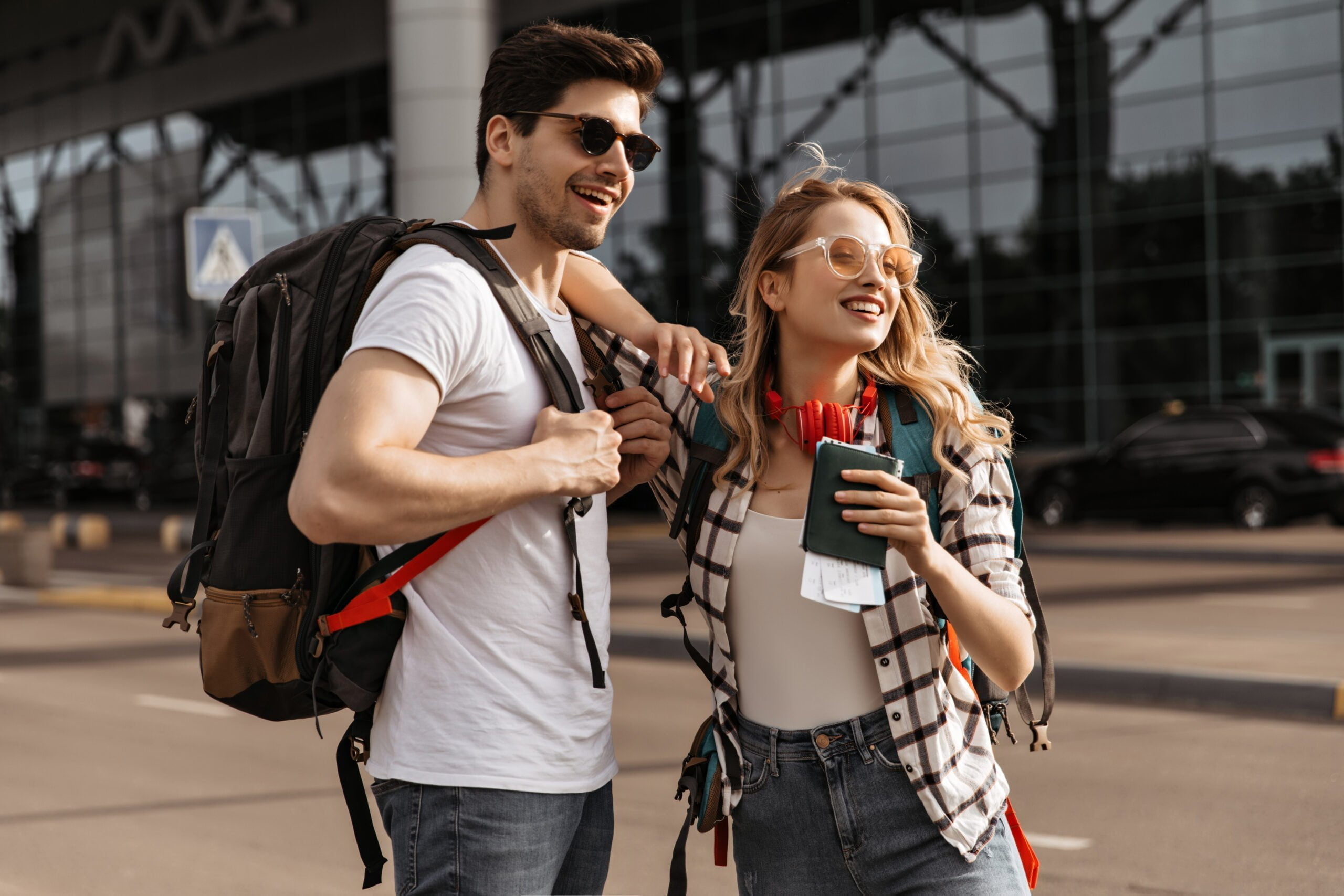 travelers with backpacks poses near modern airport scaled